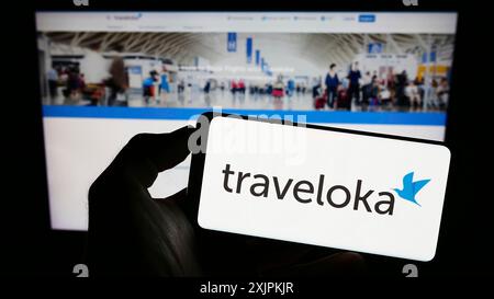 Stuttgart, Germany, 07-12-2023: Person holding cellphone with logo of Indonesian travel company Traveloka on screen in front of business webpage. Stock Photo