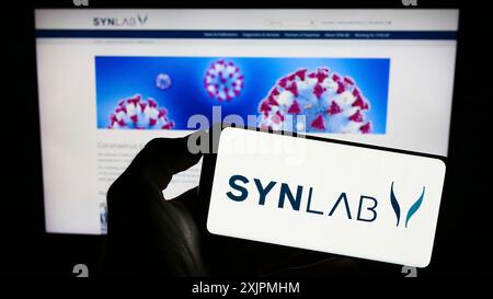 Stuttgart, Germany, 07-27-2023: Person holding cellphone with logo of medical diagnostics company SYNLAB Group on screen in front of business Stock Photo