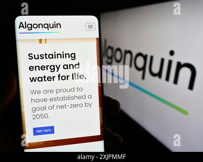 Stuttgart, Germany, 07-28-2023: Person holding smartphone with webpage of Canadian company Algonquin Power Utilities Corp. on screen with logo. Focus Stock Photo