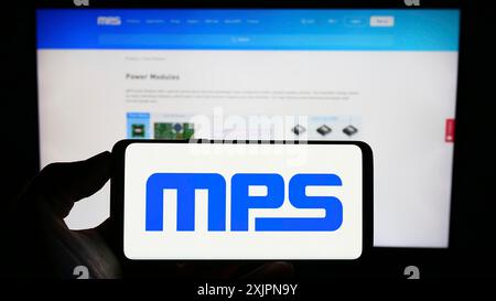 Stuttgart, Germany, 08-05-2023: Person holding cellphone with logo of American company Monolithic Power Systems Inc. (MPS) on screen in front of Stock Photo