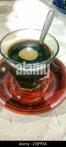 A glass of hot black coffee on a small plate Stock Photo