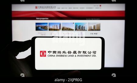 Stuttgart, Germany, 08-17-2023: Person holding cellphone with logo of China Overseas Land and Investment Limited (COLI) on screen in front of Stock Photo