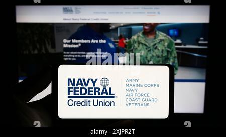 Stuttgart, Germany, 08-18-2023: Person holding smartphone with logo of financial instituation Navy Federal Credit Union on screen in front of Stock Photo