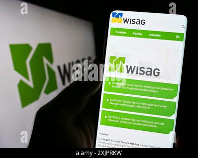 Stuttgart, Germany, 08-28-2023: Person holding cellphone with webpage of German company WISAG Dienstleistungsholding SE on screen with logo. Focus on Stock Photo