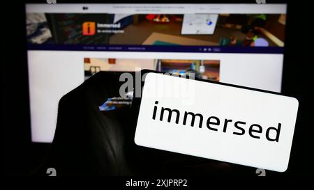 Stuttgart, Germany, 08-30-2023: Person holding mobile phone with logo of American virtual reality company Immersed Inc. on screen in front of web Stock Photo