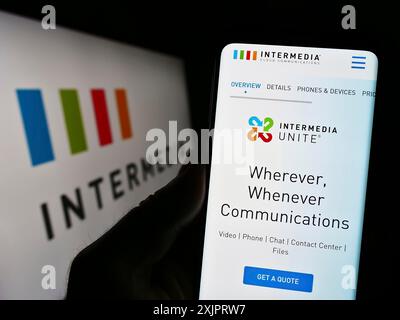 Stuttgart, Germany, 08-28-2023: Person holding smartphone with webpage of US company Intermedia Cloud Communications on screen in front of logo. Stock Photo