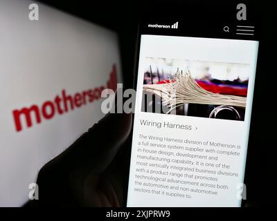 Stuttgart, Germany, 08-28-2023: Person holding smartphone with website of company Samvardhana Motherson International Ltd. on screen with logo. Focus Stock Photo