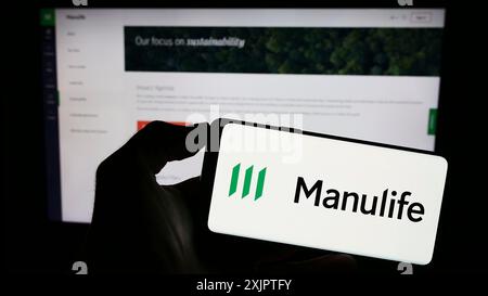 Stuttgart, Germany, 09-11-2023: Person holding smartphone with logo of Canadian company Manulife Financial Corporation on screen in front of website. Stock Photo