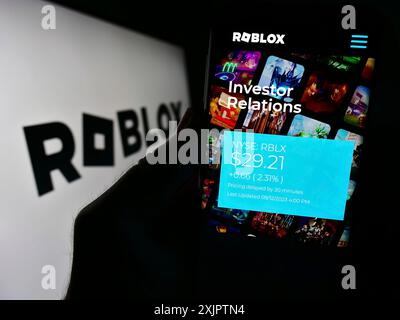 Stuttgart, Germany, 09-13-2023: Person holding smartphone with website of US video games company Roblox Corporation on screen in front of logo. Focus Stock Photo