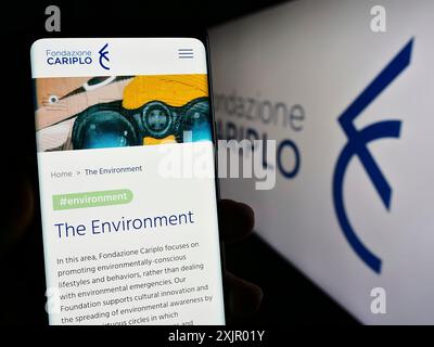 Stuttgart, Germany, 11-03-2023: Person holding smartphone with webpage of Italian charitable foundation Fondazione Cariplo in front of logo. Focus on Stock Photo