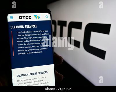 Stuttgart, Germany, 11-03-2023: Person holding cellphone with web page of US company Depository Trust and Clearing Corporation (DTCC) with logo. Stock Photo