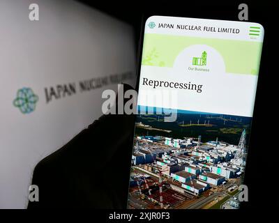 Stuttgart, Germany, 11-08-2023: Person holding smartphone with webpage of Japanese energy company Japan Nuclear Fuel Ltd. (JNFL) with logo. Focus on Stock Photo