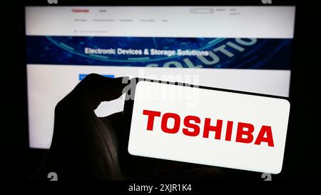 Stuttgart, Germany, 11-23-2023: Person holding cellphone with logo of Japanese electronics company Toshiba Corporation in front of business webpage. Stock Photo