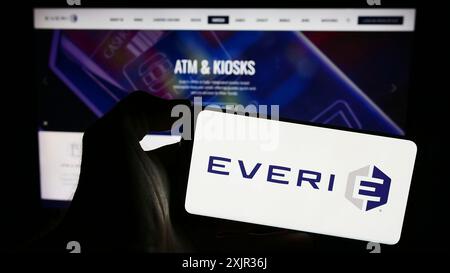 Stuttgart, Germany, 12-17-2023: Person holding smartphone with logo of US slot machine company Everi Holdings Inc. in front of website. Focus on Stock Photo