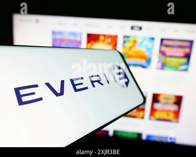 Stuttgart, Germany, 12-17-2023: Mobile phone with logo of American slot machine company Everi Holdings Inc. in front of business website. Focus on Stock Photo