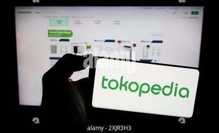 Stuttgart, Germany, 12-20-2023: Person holding cellphone with logo of Indonesian e-commerce company PT Tokopedia in front of business webpage. Focus Stock Photo