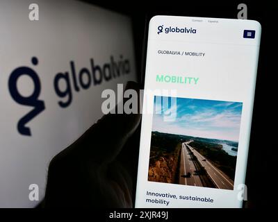 Stuttgart, Germany, 02-07-2023: Person holding cellphone with webpage of Spanish company GLOBALVIA Inversiones S.A.U. in front of logo. Focus on Stock Photo