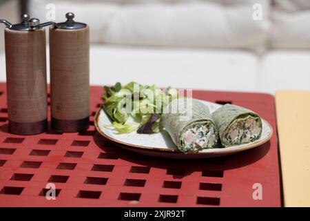 A fresh and healthy spinach wrap filled with creamy chicken salad, cut in half and displayed on a wooden board. Stock Photo