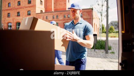 Efficient Couriers Loading and Unloading Boxes for Express Delivery with Professionalism; Delivering Packages Across Country for Fast Service. Stock Photo