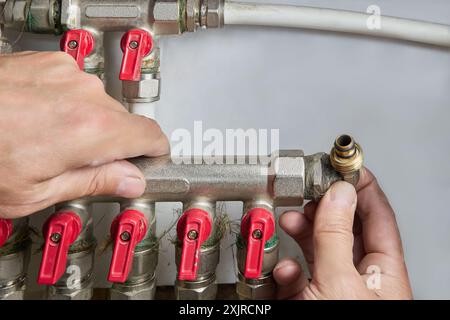 Plumber installing manifold for plastic pipes with five outlets. Stock Photo