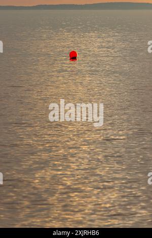 Buoy with a streak of sunlight going across the sea Stock Photo