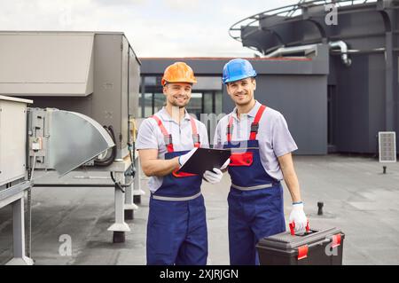 Portrait Of Workers Or Technicians Servicing Hvac Systems On A Roof Stock Photo