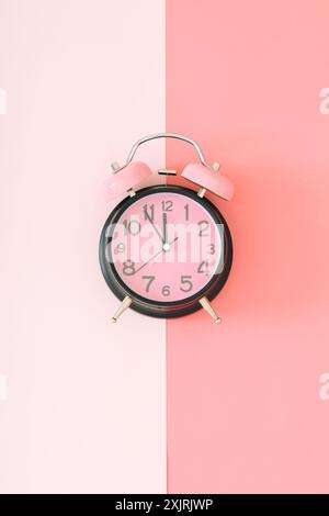 Pastel pink and black alarm clock on light and dark pastel pink background with copy space. Minimal time concept. Flat lay. Stock Photo