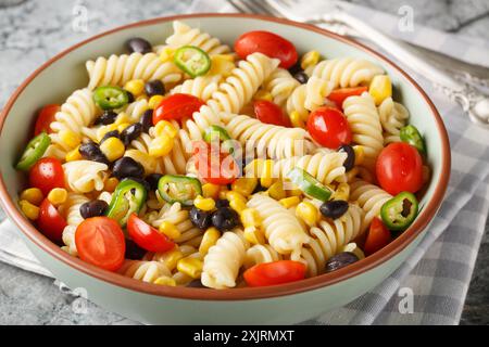 simple hearty salad of fusilli pasta, black beans, tomato and corn close-up in a plate on the table. Horizontal Stock Photo