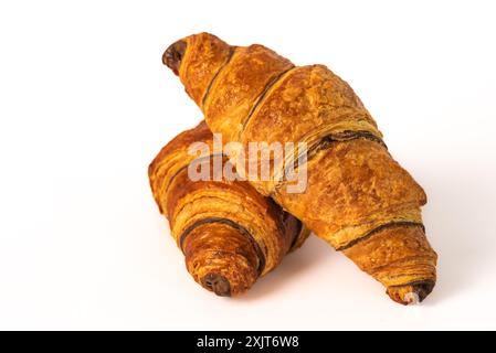 A two perfectly baked croissants, golden brown and flaky, are stacked on a white background. The croissants have a slight sheen and visible layers, su Stock Photo