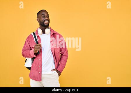 Happy young African man student standing isolated on yellow background. Stock Photo