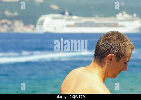 Portrait of a smiling man taken on the seashore with a cruise ship in the background. Summer in Montenegro - a tourist enjoying a holiday Stock Photo