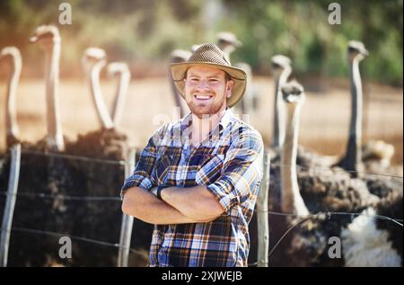 Portrait, man and ostrich on farm for agriculture, sustainability or wildlife conservation in countryside. Animal welfare, bird and male person for Stock Photo