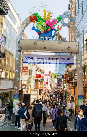 The famous entrance arch at the start of Takeshita Street in Harajuku during the day, with the street behind, crowded with shoppers in the sunshine. Stock Photo