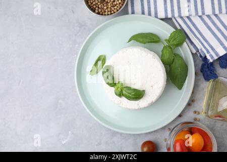 Fresh ricotta (cream cheese) and basil on gray table, flat lay. Space for text Stock Photo