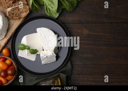 Fresh ricotta (cream cheese), basil and other products on wooden table, flat lay. Space for text Stock Photo