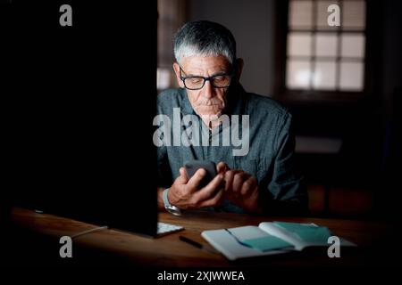 Mature man, typing and glasses for cellphone, notes and working late in home office, entrepreneur and texting. Vision, serious and notebook for plan Stock Photo