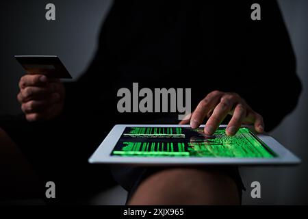 Hacker, hands or tablet at night with credit card, online scam or programming for theft. Man, cyber crime or operating system on tech for black market Stock Photo