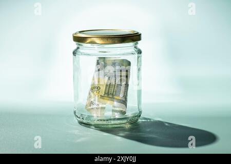 Five euro banknote in a glass with turquoise background and hard shadow Stock Photo