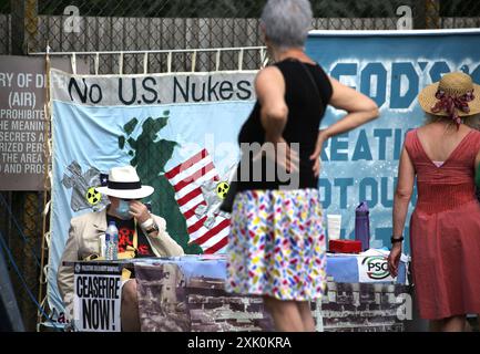 July 20, 2024, Lakenheath, England, UK: Protesters gather by a sign attached to the fencing saying ''˜No to US Nukes' outside the air force base in Lakenheath, during the demonstration. The protest was organised by the Campaign for Nuclear Disarmament (CND), whose supporters oppose the potential return of nuclear weapons to military bases in the UK, such as RAF Lakenheath after it was reported that the US intends to resite nuclear bombs at the base. After sustained protest nuclear weapons were removed from Lakenheath in 2008. (Credit Image: © Martin Pope/ZUMA Press Wire) EDITORIAL USAGE ONLY Stock Photo