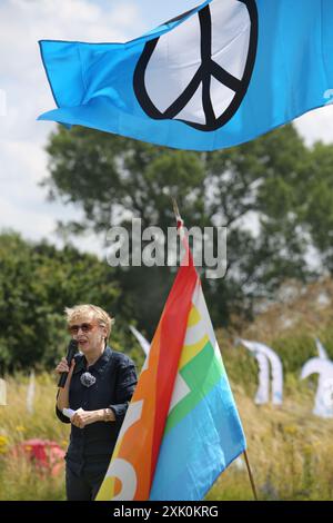 July 20, 2024, Lakenheath, England, UK: KATE HUDSON General Secretary of CND speaks to gathered protesters outside the air force base flanked by flags in Lakenheath, during the demonstration. The protest was organised by the Campaign for Nuclear Disarmament (CND), whose supporters oppose the potential return of nuclear weapons to military bases in the UK, such as RAF Lakenheath after it was reported that the US intends to resite nuclear bombs at the base. After sustained protest nuclear weapons were removed from Lakenheath in 2008. (Credit Image: © Martin Pope/ZUMA Press Wire) EDITORIAL USAGE Stock Photo