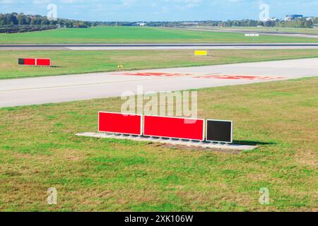 Red and black sign is on the grass next to a runway. Runway for touch off Stock Photo