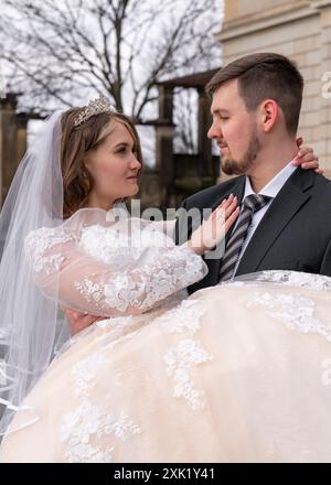 The groom gently holds the young bride in his arms. Close-up. Love Stock Photo