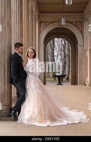 Wedding portrait of a young beautiful modern couple. The groom hugs the bride, she clung to him, holding a bouquet of white roses in her hands. touch, Stock Photo