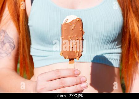 A young woman enjoys a chocolate and almond covered ice cream on a sunny summer day Stock Photo