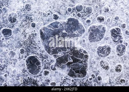 A close-up view of intriguing patterns formed by ice bubbles trapped beneath the frozen surface of a lake in Lofoten, Norway, highlighting nature's in Stock Photo