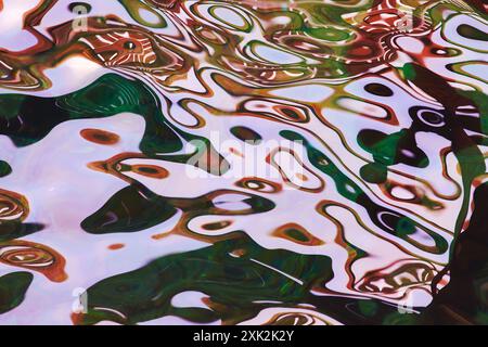 This stunning photo captures abstract water reflections with swirling patterns of green and brown, embodying a serene visual scene in Lofoten, Norway. Stock Photo