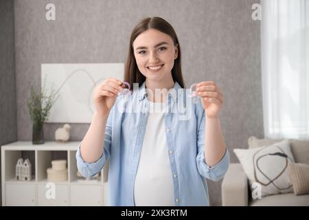 Expecting twins. Pregnant woman holding two pacifiers at home Stock Photo