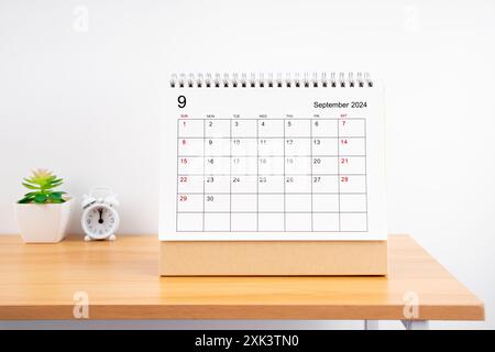 September 2024, Monthly desk calendar for 2024 year on wooden table with alarm clock. Stock Photo