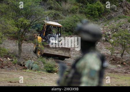 Queretaro, Mexico. 19th July, 2024. A member of the Guardia Nacional guards the place where an excavation is carried out. During a search day, the Desaparecidos Querétaro collective placed a cross that symbolizes peace on a property in the community of Santa Barbara de la Cueva, in the municipality of San Juan del Río, Querétaro, where 3 bodies have previously been found. They have already been identified. Canines from the National Guard also participated in the search. Credit: SOPA Images Limited/Alamy Live News Stock Photo