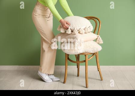 Woman putting pillow on chair in room Stock Photo